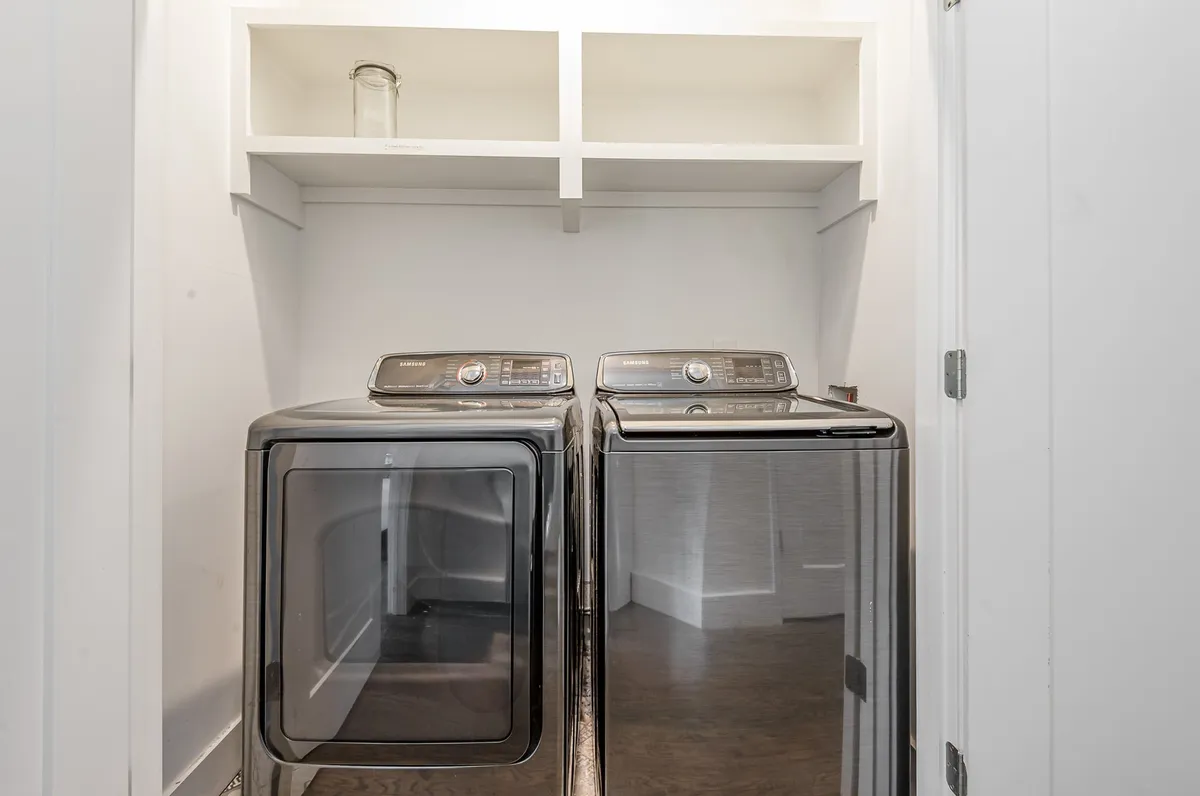 A practical, well-organized laundry area with a washer, dryer, and shelves for storage. The space looks clean and functional, designed for convenience during longer stays or for families needing to keep up with laundry on the go.